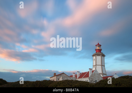 Espichel Leuchtturm bei Sonnenuntergang mit rosa Wolken und blauer Himmel, Espichel Kap, Sesimbra, Portugal Stockfoto