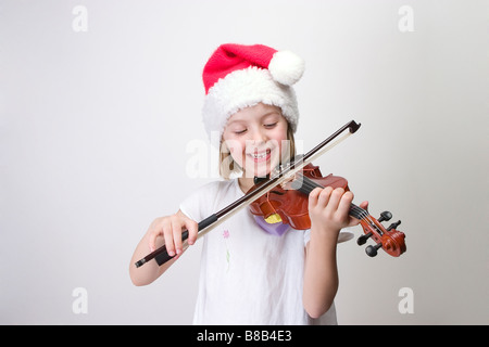 Mädchen - 6 Jahre alt spielt Violine in Nikolausmütze Stockfoto