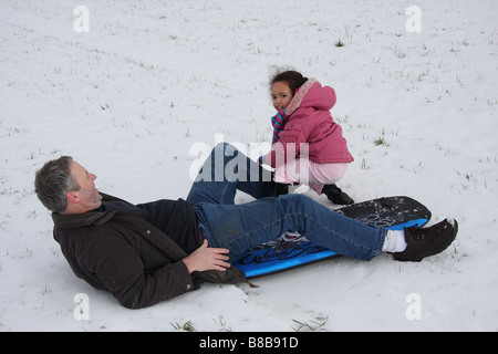 Snowboard Spielspaß weißen Vater Tochter Toddlerl schwarzen ethnischen Mischlinge glücklich lächelnde spielen Schnee Eis junge Stockfoto