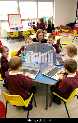 Lehrer arbeiten mit Grundschüler auf Laptop-Computern Stockfoto