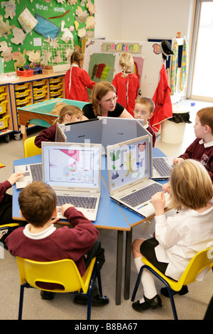 Lehrer arbeiten mit Grundschüler auf Laptop-Computern Stockfoto