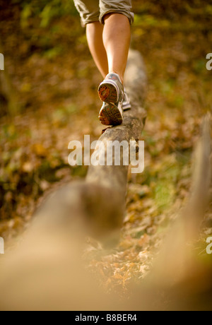 Frau zu Fuß über gefallenen Baumstamm im Wald Stockfoto