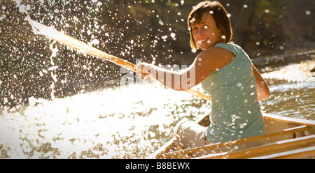 Frau spritzt Wasser hinter Kanu im Fluss Stockfoto