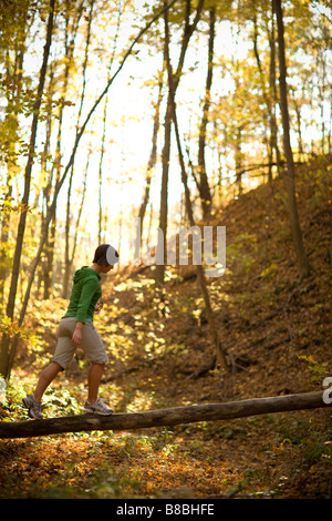 Frau balancieren auf gefallenen Baumstamm im Wald Stockfoto
