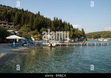 Ansicht der Taverne Agni Kiesel Strand Seite, Liegestühle, Boote, zwei Damen sitzen auf einem Steg, Korfu, Kerkyra Griechenland Europa EU-Landschaft Stockfoto