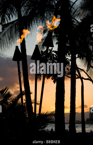 Sonnenuntergang und Tiki Fackeln, Waikiki Beach, Honolulu, Oahu, Hawaii. Stockfoto