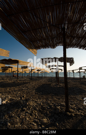 Stroh Schattierungen Zelte auf einem Kiesstrand in Bar, Montenegro am abend sonnenuntergang sonne Licht Stockfoto