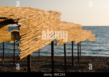 Stroh Schattierungen Zelte auf einem Kiesstrand in Bar, Montenegro am abend sonnenuntergang sonne Licht Stockfoto