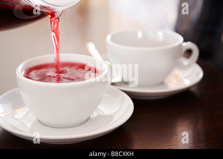 Eine pflanzliche Früchtetee Gießen in eine weiße Tasse Stockfoto