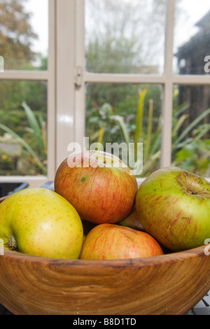 Äpfel in Holzschale durch Fenster Stockfoto