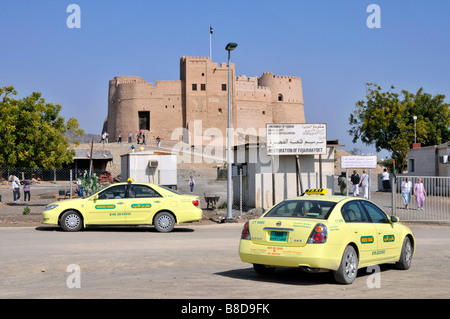 Sightseeing-Touristen & Taxi Taxis vor dem Eingang zu historischen Restauriertes Fujairah Fort und Museumsattraktion in den Vereinigten Arabischen Emiraten VAE Naher Osten Stockfoto