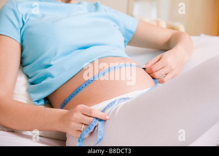 Schwangere Frau Messung Magen auf Bett Stockfoto