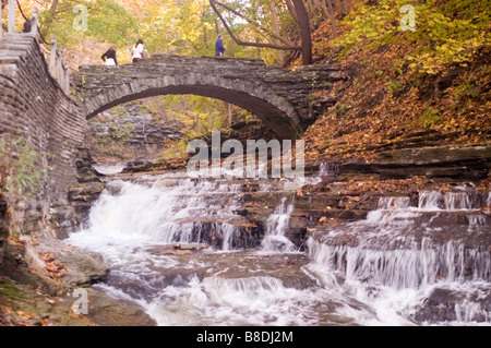Der malerische Wasserfallpfad Cascadilla Creek Gorge mit Steinbrücke und Herbstlaub in Ithaca, NY, USA. Stockfoto