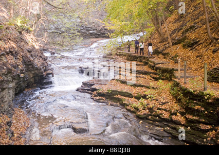 Malerischer Wasserfallpfad in der Schlucht des Cascadilla Creek mit Wanderern im Herbst, Ithaca, NY, USA. Stockfoto