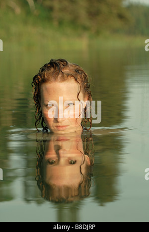 Frau im See mit Gesicht spiegelt sich im Wasser, See Katherine Riding Mountain National Park, Manitoba, Kanada Stockfoto