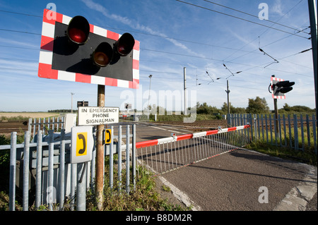 Bahnübergang mit Warnung Lichter blinken und Barrieren auf der Ostküste Hauptstrecke Eisenbahn in Großbritannien Stockfoto