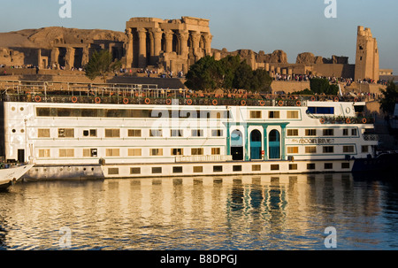 Kreuzfahrt-Boot am Flussufer mit Ruinen der Kom Ombo Tempel im Hintergrund. Stockfoto