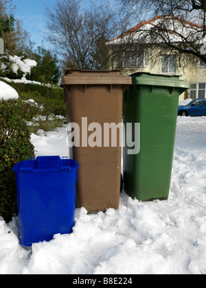 Grün braun Wheelie Lagerplätzen im Schnee draußen Haus wartet auf Sammlung Cheam Surrey England Stockfoto