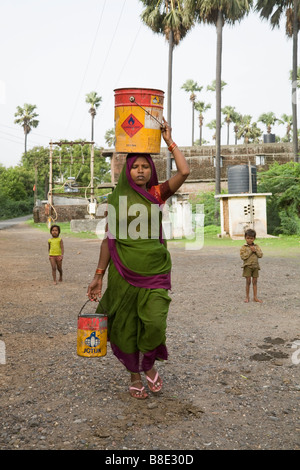Frauen, die Wasser aus einem Brunnen in der Dose auf den Kopf. Hazira, Surat, Gujarat. Indien. Stockfoto