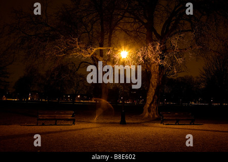 Parkbänke und ein Licht in der Nacht in Clapham Common, Südlondon. Stockfoto