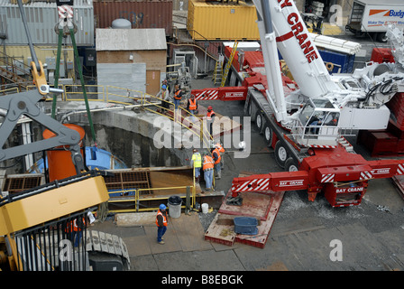 Bauarbeiter vorzubereiten, die 100-Tonnen-Schneidkopf von einer Tunnelbohrmaschine in einen Schacht in einem Plenarsaal zu senken Stockfoto