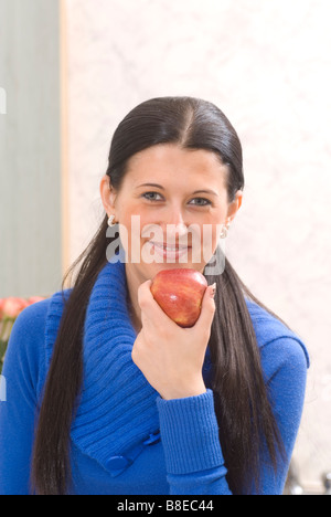 Junge Frau hält einen roten Apfel Obst und Blick in die Kamera Stockfoto