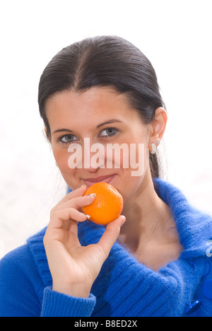Schöne junge Frau hält eine Mandarine Frucht
