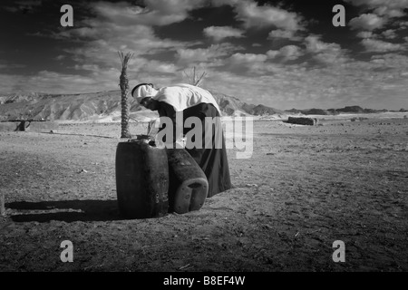 Schwarz / weiß Bild eines Beduinen männlichen Kanister einfüllen von Wasser in Ägypten Stockfoto