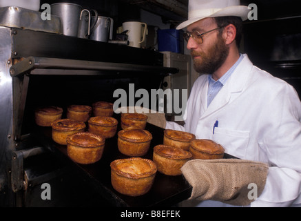 Ein Bäcker aus Ye Olde Pork Pie Shoppe in Melton Mowbray hält ein Tablett mit Schweinefleischpasteten frisch aus dem Ofen. Leicestershire. UK Stockfoto