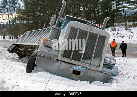 Sattelschlepper in Graben im Schnee mit Männern auf Stockfoto