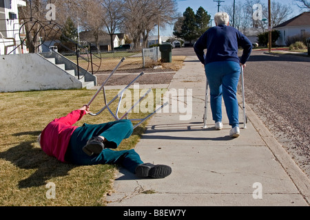 Zwei ältere Senioren gehen weg mit Wanderern, die Frau stolperte des Mannes, lustig, 1 von 4 in Reihe fiel Stockfoto