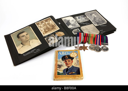 Ein ww2 Veteran s Photo Album mit einer Gruppe von Medaillen und eine Rekrutierung Buch vor einem weißen Hintergrund Stockfoto