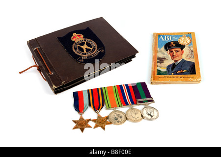 Ein ww2 Veteran s Photo Album mit einer Gruppe von Medaillen und eine Rekrutierung Buch vor einem weißen Hintergrund Stockfoto