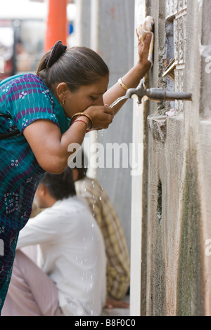 Indische Frau Trinkwasser aus öffentlichen Leitung im Marketplace, Jaipur, Indien Stockfoto