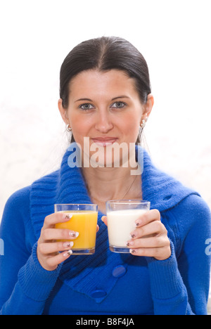 Junge Frau hält Gläser Orangensaft und Milch