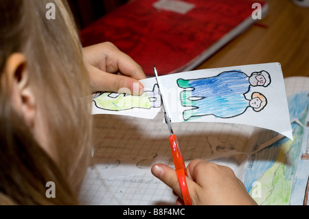 Ein junges Mädchen ist damit beschäftigt, Papierfiguren auszuschneiden Stockfoto