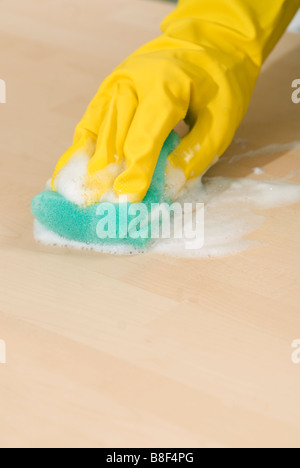 Nahaufnahme von Frauenhand in gelbe Gummihandschuhe, eine Oberfläche mit einem Schwamm schrubben Stockfoto
