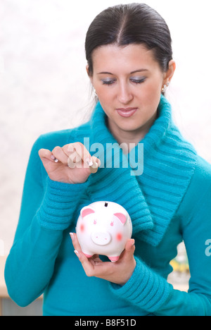 Frau spart Geld im Sparschwein Stockfoto