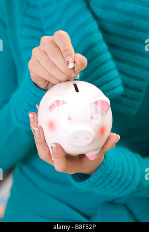 Frau spart Geld im Sparschwein Stockfoto