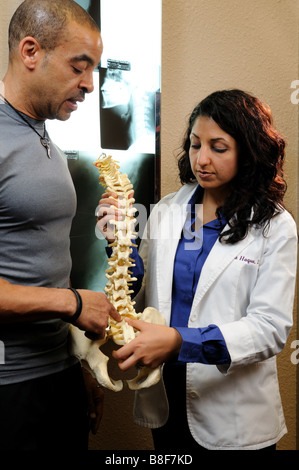 Frau Chiropraktiker beschreibt eine Verletzung bei einem Patienten mit Röntgenstrahlen Kunststoff Wirbelsäule Stockfoto