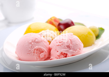 Zwei Kugeln Erdbeereis mit Obst auf einer Platte angeordnet Stockfoto