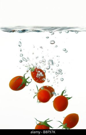 Cherry-Tomaten in Wasser mit Wasserblasen fallen Stockfoto