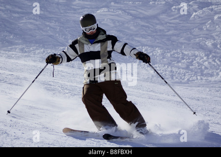 Junge Skifahrer in schwarzen und weißen Jacke und braunen Helm Parallel auf einen Parkgestalter Lauf in Französisch Resort von Méribel anhalten. Stockfoto