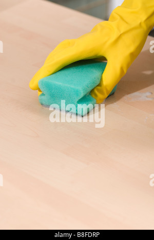 Nahaufnahme von Frauenhand in gelbe Gummihandschuhe, eine Oberfläche mit einem Schwamm schrubben Stockfoto