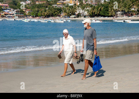 älteres paar zügig barfuß auf dem Sand am Rande der Hafen Hafen von Puerto Escondido, Oaxaca, Mexiko Stockfoto