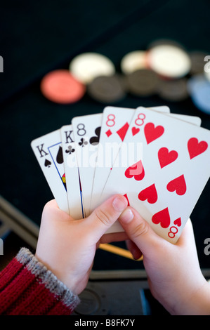 Junges Kind hält eine Hand Full House Poker Stockfoto