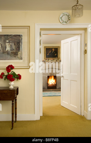 UK. Ein Blick durch eine offene Tür zu einem gemütlichen Kaminfeuer in einem traditionellen Haus Rezeption Zimmer. Stockfoto