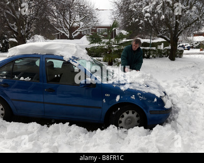 Reinigung von Schnee von einem Auto nach starkem Schneefall Surrey England Stockfoto