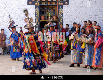 Eine bhutanische Publikum in nationalen Abendkleidung Uhren als Musiker schwarzen Hut Tänzerin bei den Festspielen von Trashigang begleiten. Stockfoto