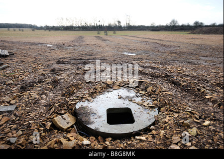 KONKRETE ZUGANGSSCHACHT ZUM VIELFÄLTIGEN ABSCHNITT HITZE BODENANLAGE QUELLE GELEGT IN EINEM FELD NEBEN EINE ENERGIE EFFIZIENTE HEIMAT GROßBRITANNIEN Stockfoto